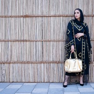 Stylish woman in a black and gold abaya in Dubai, showcasing traditional fashion with a modern twist.