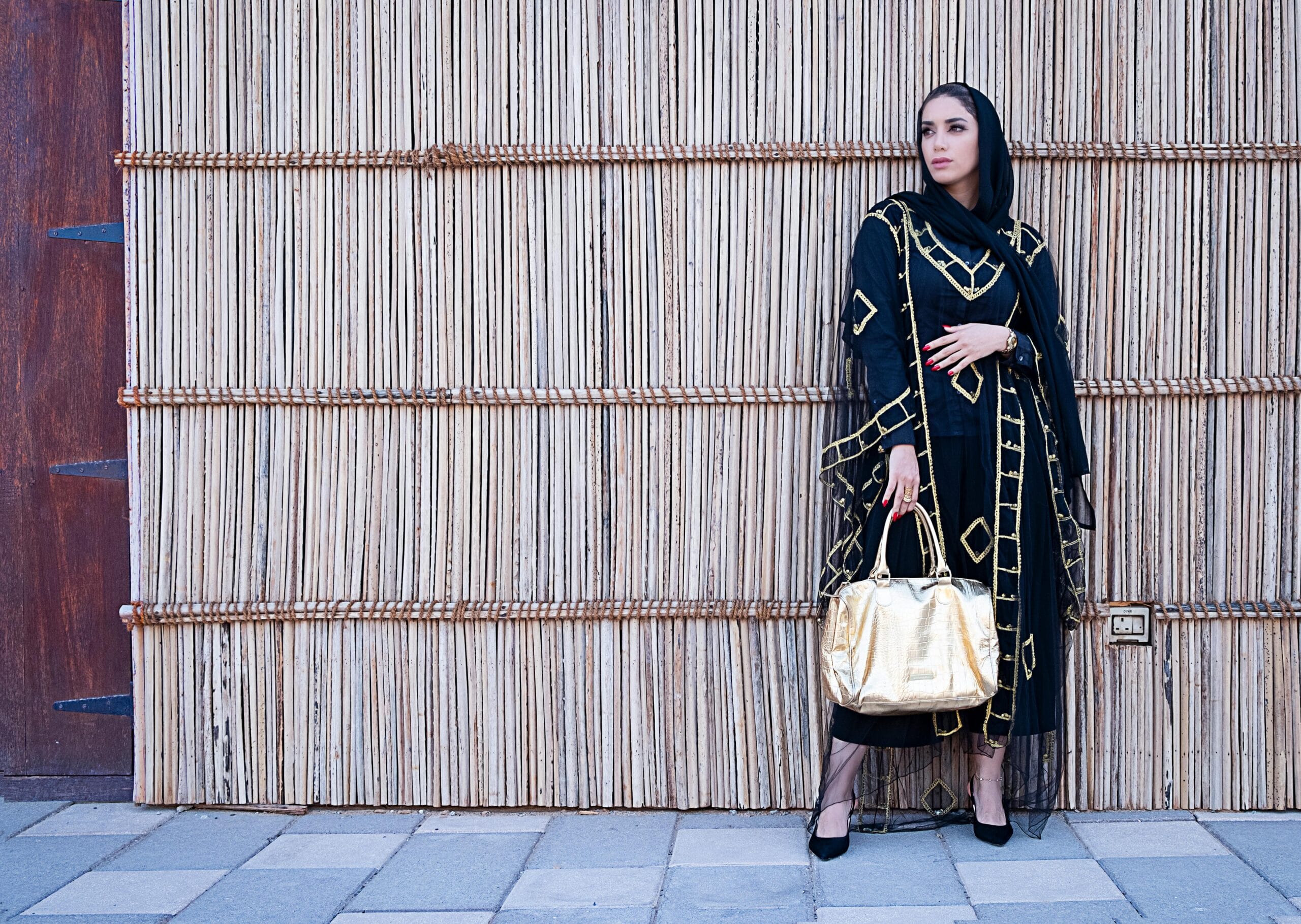 Stylish woman in a black and gold abaya in Dubai, showcasing traditional fashion with a modern twist.