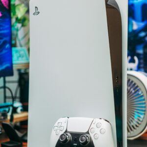 Close-up of PlayStation 5 and controller in an indoor gaming setup.