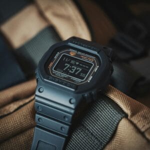 Close-up of a Casio G-Shock wristwatch resting on a textured backpack, ideal for outdoor adventures.