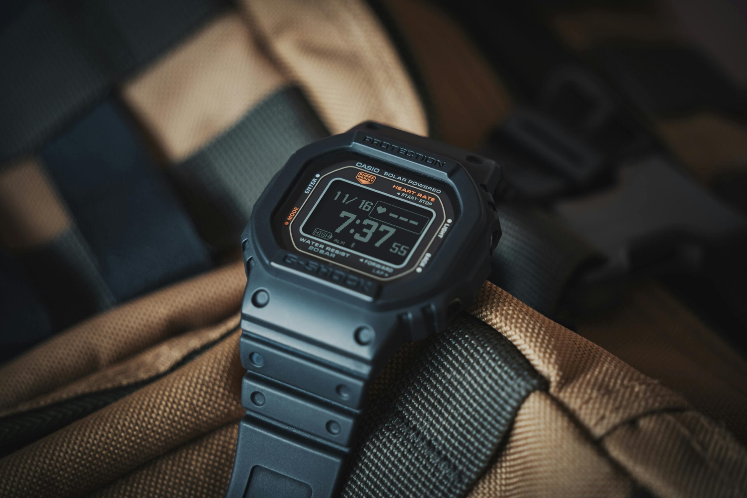 Close-up of a Casio G-Shock wristwatch resting on a textured backpack, ideal for outdoor adventures.