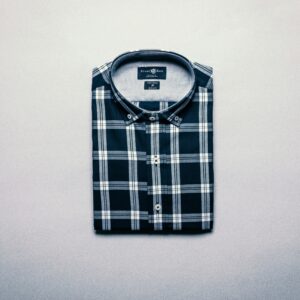 Neatly folded plaid shirt displayed on a flat gray surface, top view.