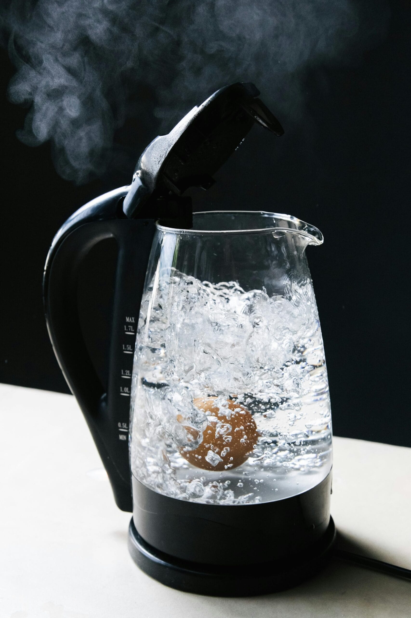 Close-up of an electric kettle with an egg boiling and steam rising, creating a dramatic scene.